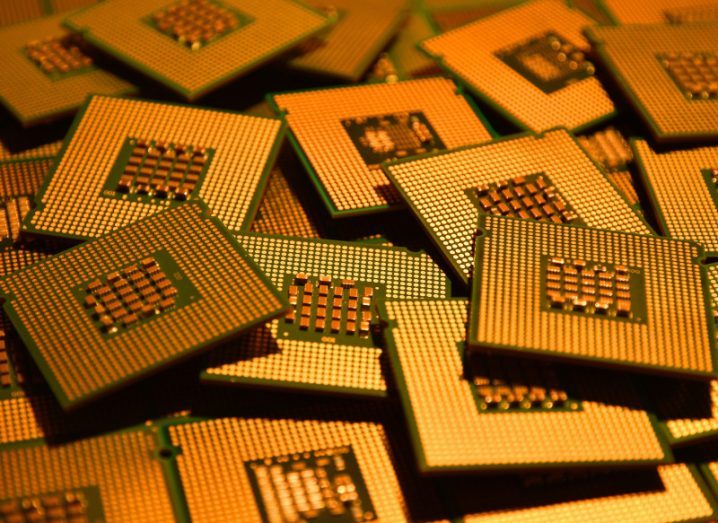 A bunch of gold computer chip processors lying on top of each other.