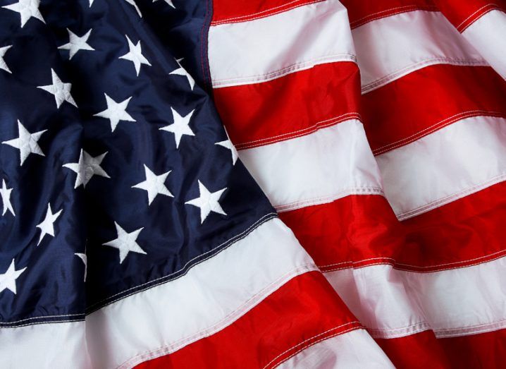 A close-up of a textured US flag with the white stars on a blue background and red and white stripes.