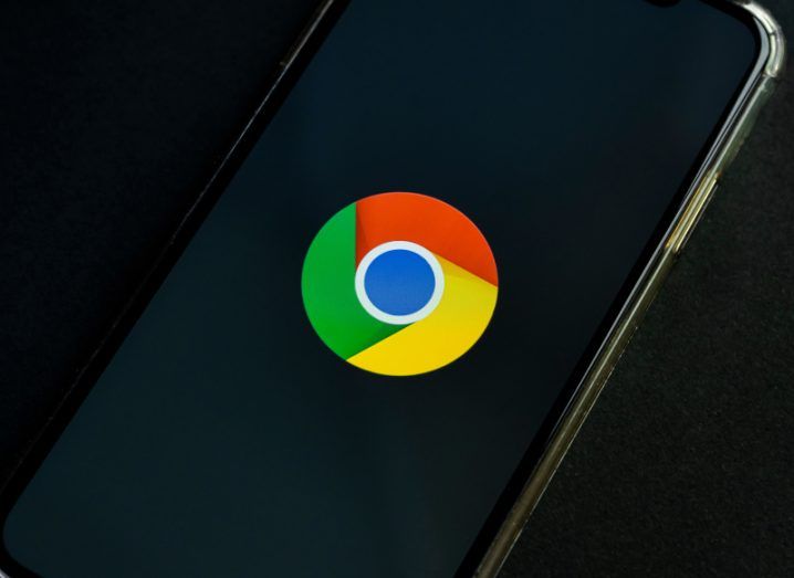 The Google Chrome logo on a smartphone screen. The phone is laying on a black surface.