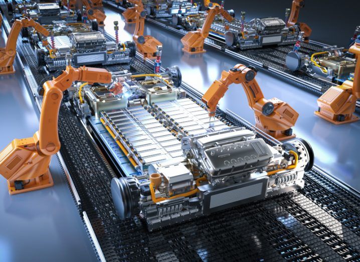 An assembly line of EV batteries with robotic arms working on them.
