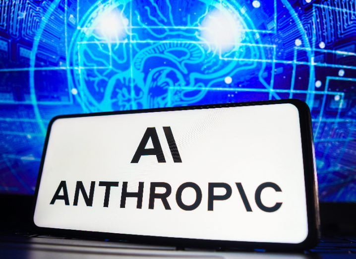 The Anthropic logo and name on a white rectangular sign in front a neon blue background.