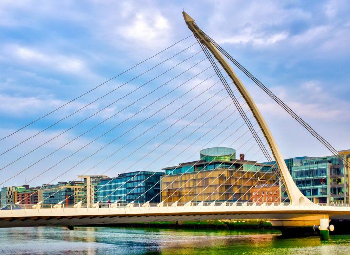 Photo of the Samuel Beckett Bridge in Dublin, Ireland. The river Liffey flows below and buildings can be seen in the background.
