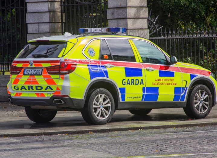 A Garda car with green and blue colours on it parked on a road.