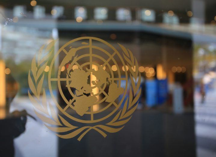 The UN logo in gold on a glass pane.