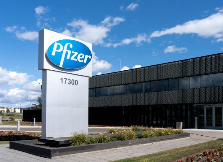 The front of a building with the Pfizer logo on it and a car park outside it.