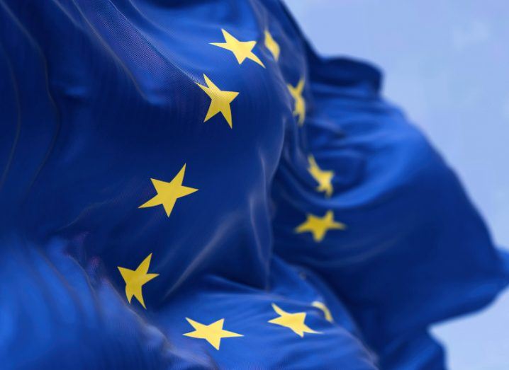 A close-up image of an EU flag waving, with a blue background behind it.