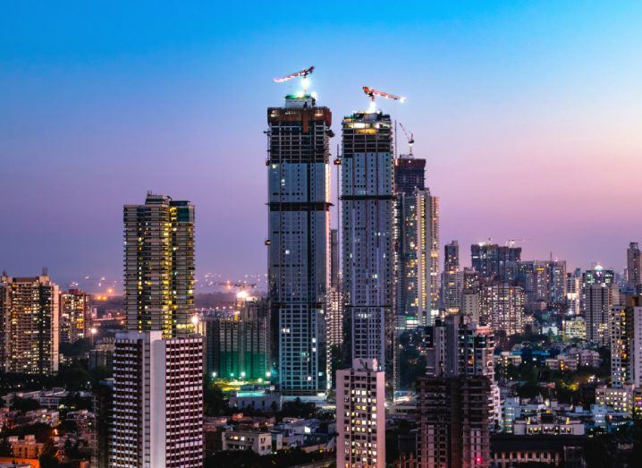 The skyline of Mumbai in India with tall buildings and cranes on top.