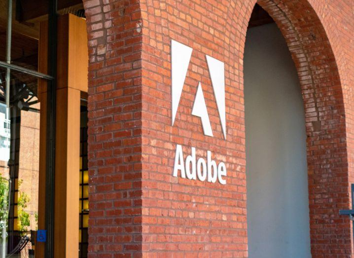 A white Adobe logo on the side of a red brick building.