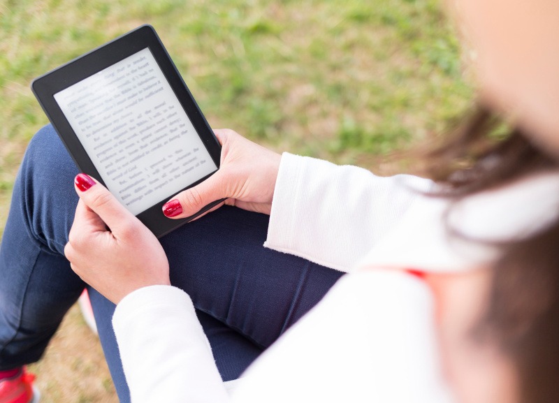 Woman using a Kindle in a park.