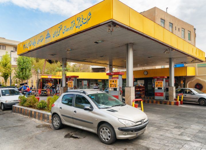 A yellow petrol station with cars in front of it.