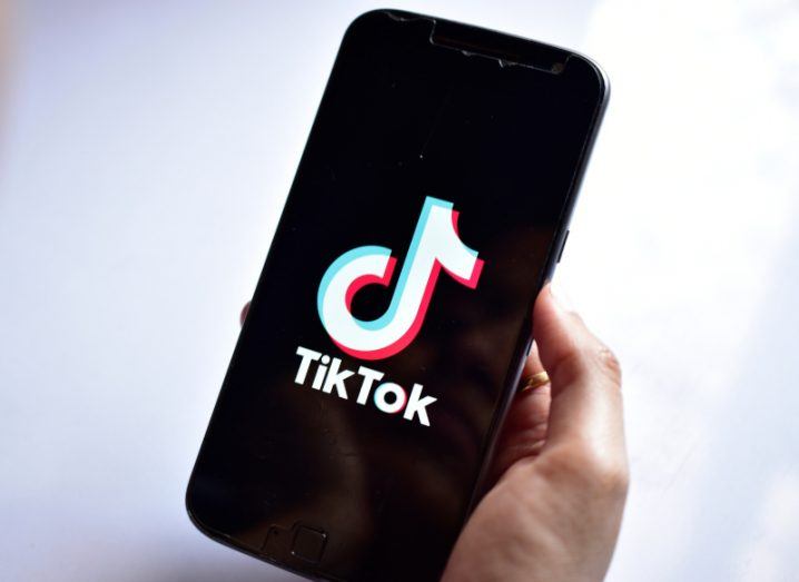 The TikTok logo on a smartphone, which is held in a person's hand.