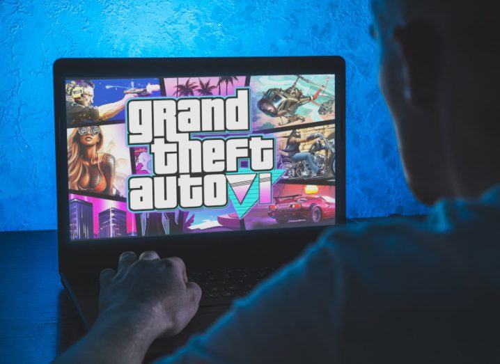 A person typing on a laptop that has the Grand Theft Auto 6 or GTA 6 logo on the screen.
