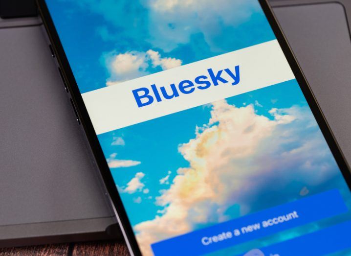 The Bluesky logo on a smartphone, which is laying on a table.