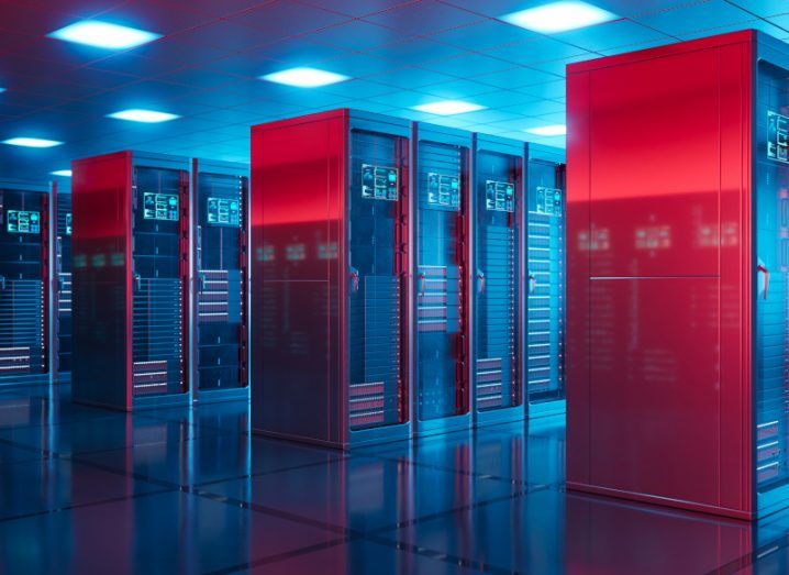 A server room inside a data centre, with rows of servers and blue lights on the ceiling. Red lighting is reflecting off of the sides of the servers.