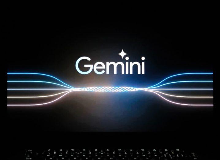 A laptop screen with the Google Gemini AI logo on it, and blue and orange lines below it.