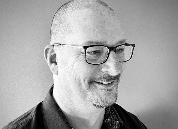A black and white image a man with glasses smiling. He is Kyndryl's Martin Summers.