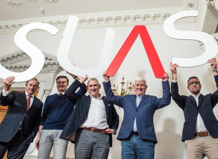Five men standing together holding up paper letters to show the logo of Suas Aerospace.