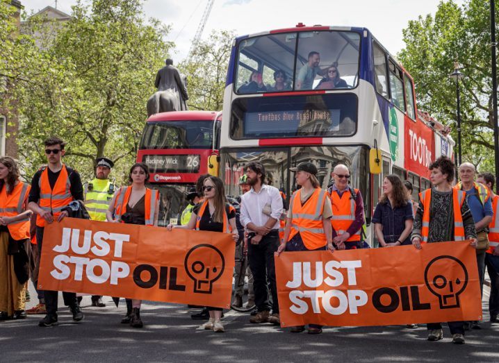 Just Stop Oil protestors marching in the streets of London with two buses behind them.