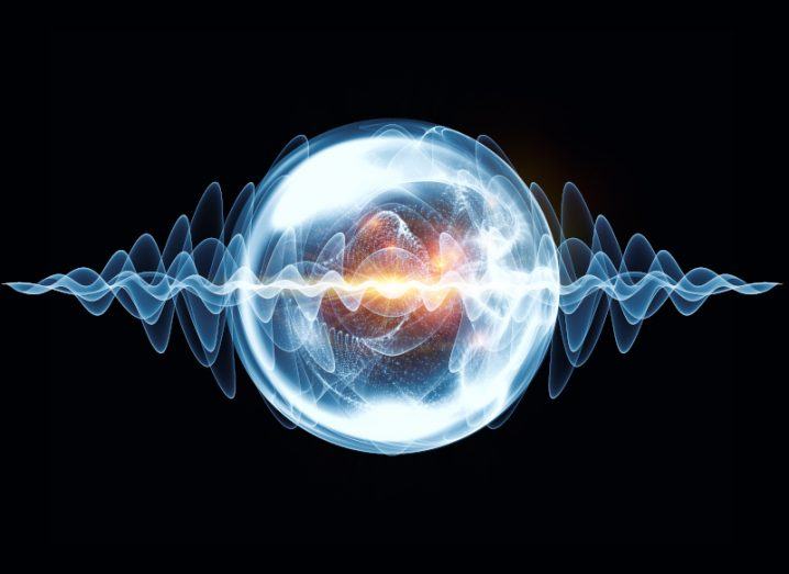 A large blue light orb with blue wave lines passing through it against a blue background, symbolising a quantum computing concept.