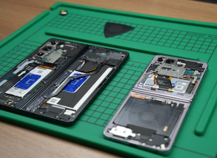 A close-up of a deconstructed Samsung smartphone on a green workstation.
