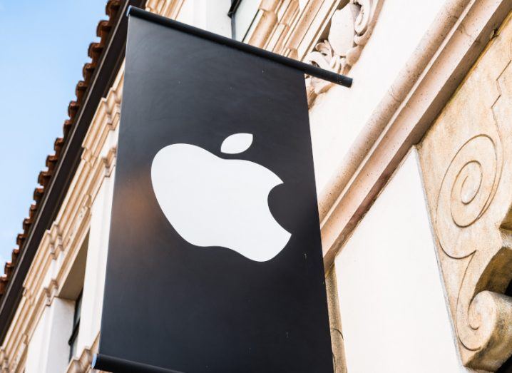 The Apple logo on a black banner hanging from the side of a building.