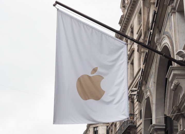The Apple logo on a white flag hanging from the side of a building.