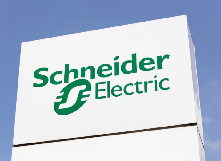 The Schneider Electric logo on a white sign with a blue sky in the background.