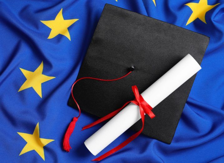 A black graduation cap and diploma on top of an EU flag.