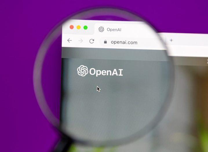 A computer screen with the OpenAI logo on a website, which is being focused on by a magnifying glass. There is a purple background behind the screen.