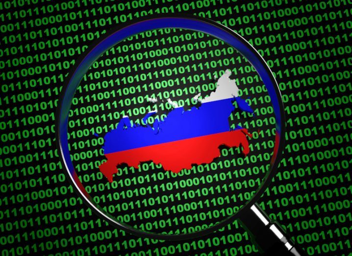 Illustration of Russia with the Russian flag over it and green binary code in the background. A magnifying glass is surrounding Russia.