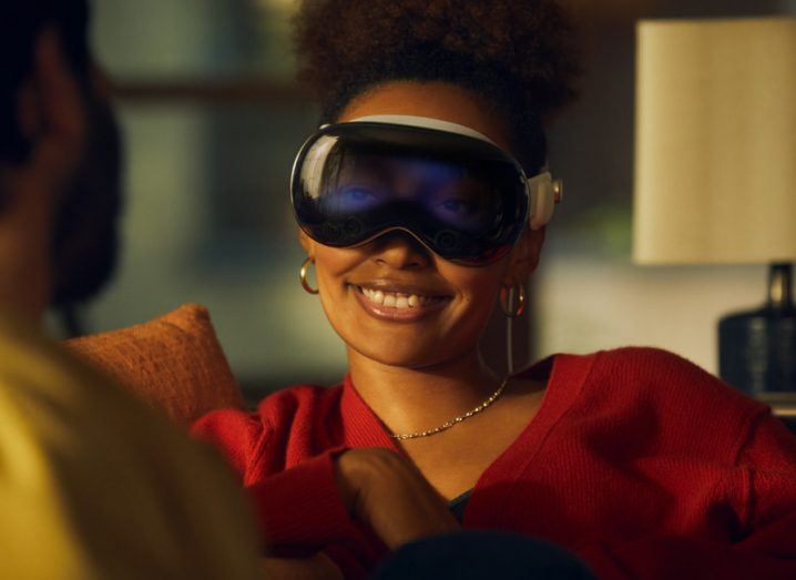 A woman wearing the Apple Vision Pro VR headset and smiling.