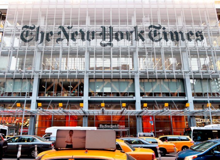 The front of The New York Times office building with several cars and taxis on the road in front of it.