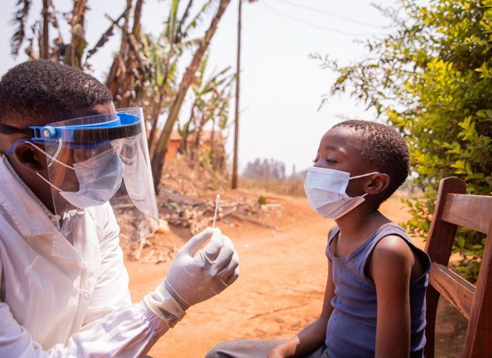 Doctor performing a test for malaria on a child in Africa.