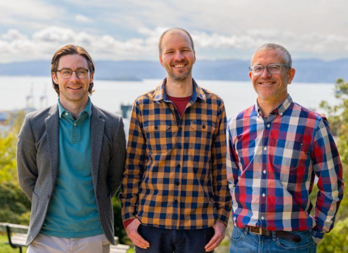 Three men standing next to each other with some trees, a body of water and a cloudy sky in the background. They are the co-founders of Marama Labs.