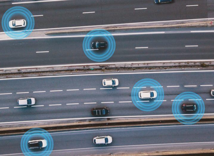 Aerial view of cars on a road, with certain cars having blue circles around them. Used to show the concept of connected transport technology.