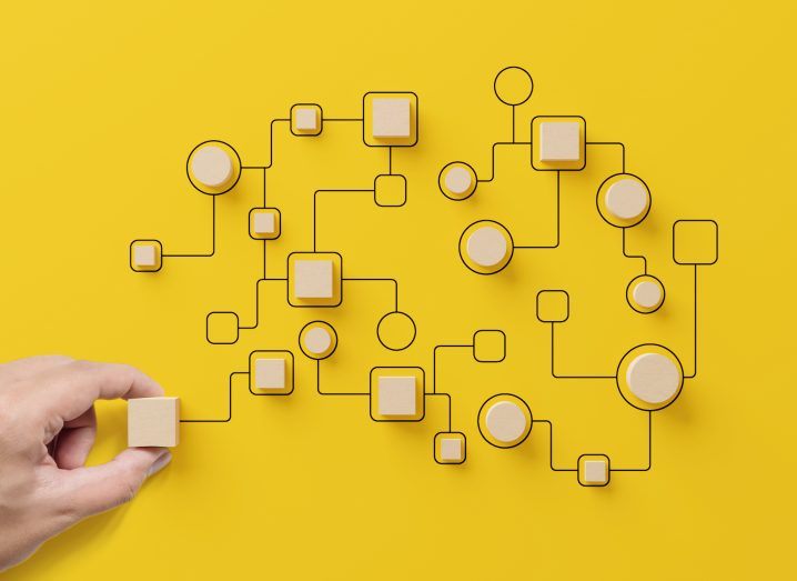 Illustration of workflow on a bright yellow background with a human hand holding a wooden block.