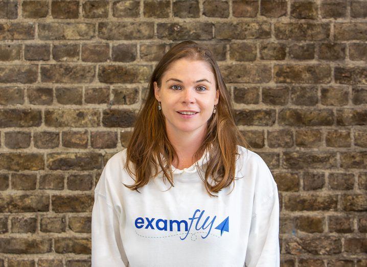 Headshot of Dee Lyons wearing a jumper with Examfly written on it. Behind her is a brick wall.