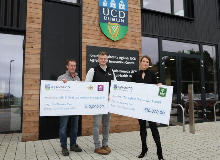 Two men and a woman standing in front of a UCD building, holding two big cheques. They are part of Moonsyst and PitSeal, two start-ups that joined the AgTechUCD accelerator.