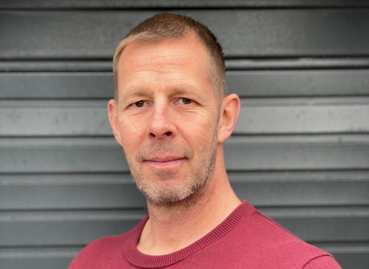 A man wearing a red T-shirt stands in front of a grey wall. He is Paul Scott, chief technical officer at Matrix Booking.