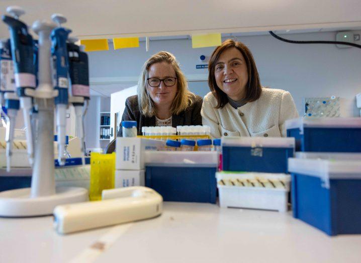 Two women in a lab with test tubes and other lab equipment in the foreground.