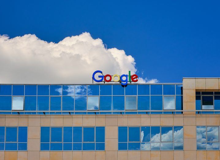 Google logo on a building with a blue sky in the background.