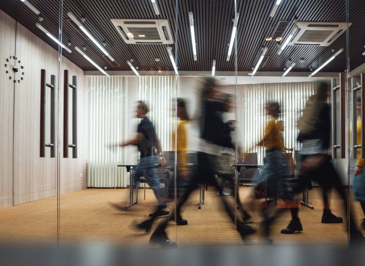 Silhouette of people walking around in an office room in motion.