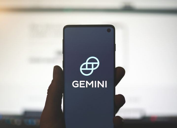 A person's hand holding a smartphone with the Gemini logo on the screen.