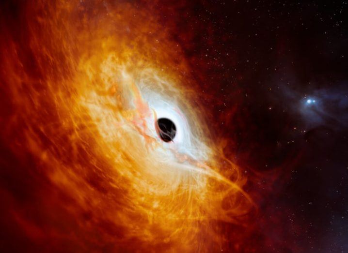 An artistic representation of a quasar, with red and orange gases swirling around a black hole, with bright light surrounding the edges of the black hole as the gases get pulled towards its centre.