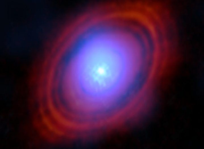 A blue star with red rings and a dark blue ring surrounding it. It is believed the blue ring is water vapour and is located where planets would typically form around a star.