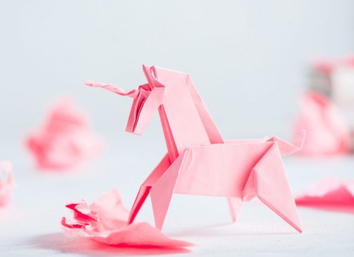 A pink origami unicorn surrounded by crumpled paper balls.