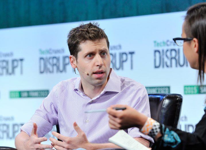 OpenAI CEO Sam Altman sitting and speaking to a woman at an event.