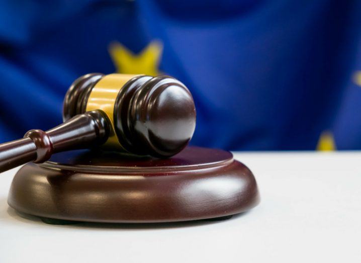 A gavel on a table with an EU flag in the background. Used for the concept of DMA enforcement and investigations.