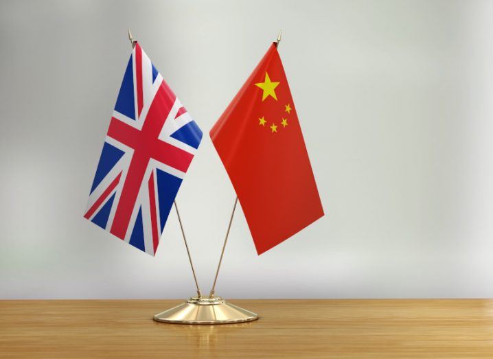 The UK and Chinese flags together on a wooden table.