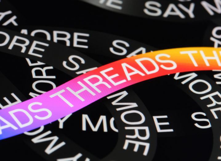 The Threads logo on a multi-coloured line on top of multiple black lines with 'say more' written on them.